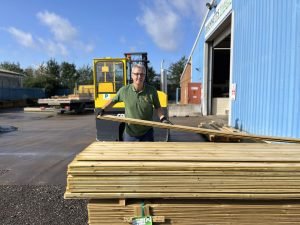 Man organising timber in yard near trees